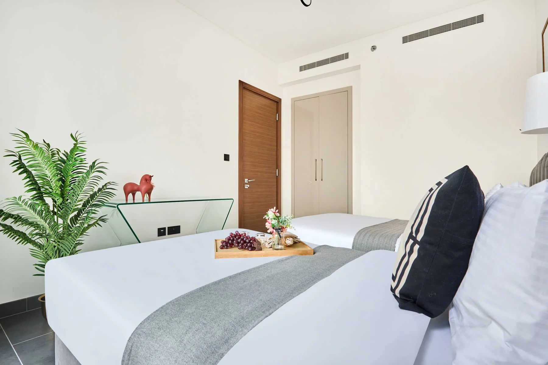 Un dormitorio luminoso con una cama bien hecha y un helecho en maceta.