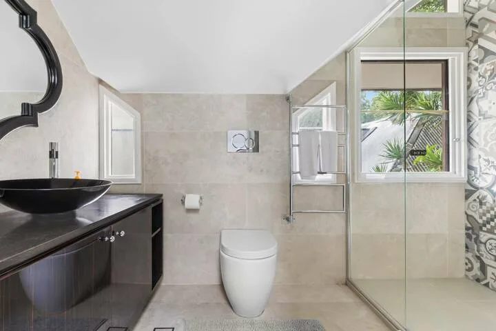 Un baño luminoso con lavabo, inodoro y ducha de vidrio.