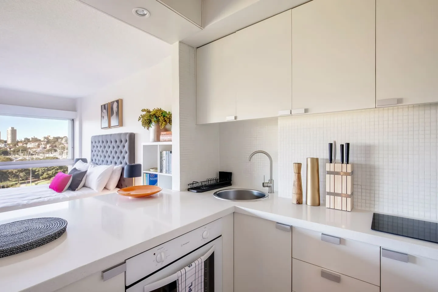 Una cocina luminosa y abierta con encimera blanca y una sala de estar contigua.