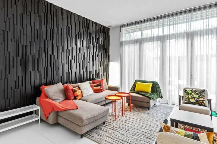 Una sala de estar moderna con asientos seccionales y grandes ventanas con cortinas.