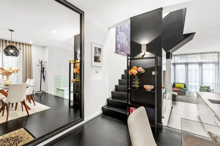 Un interior moderno de planta abierta conecta un comedor con una sala de estar y una escalera.