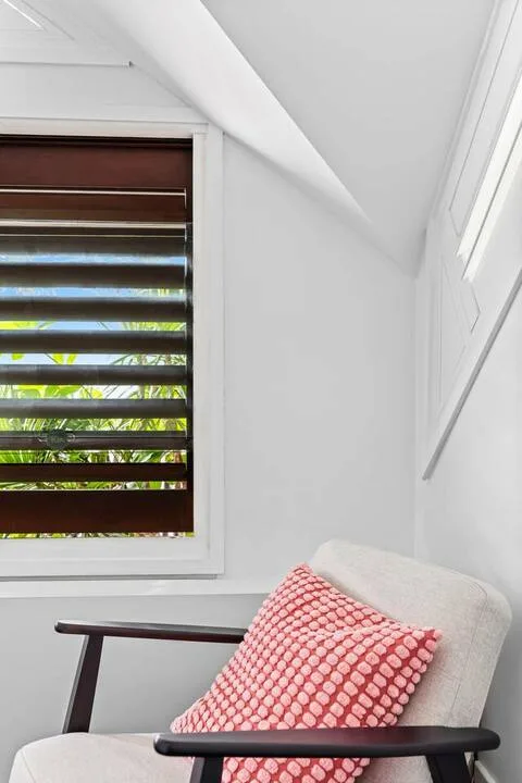 Una zona de estar luminosa con un asiento tapizado junto a una ventana con persiana a rayas.