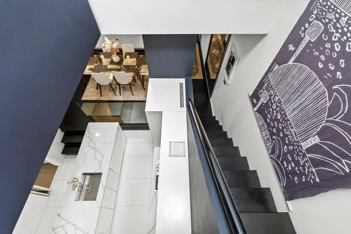 Una escalera interior moderna da a un comedor y una cocina.