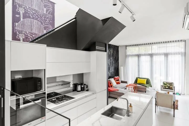 Una cocina abierta y luminosa junto a la sala de estar, con una isla central y grandes ventanales.