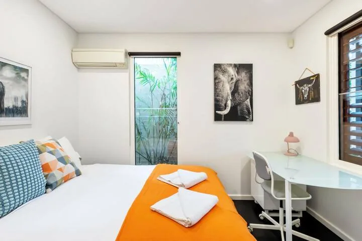 Un dormitorio con una cama y un escritorio junto a la ventana.