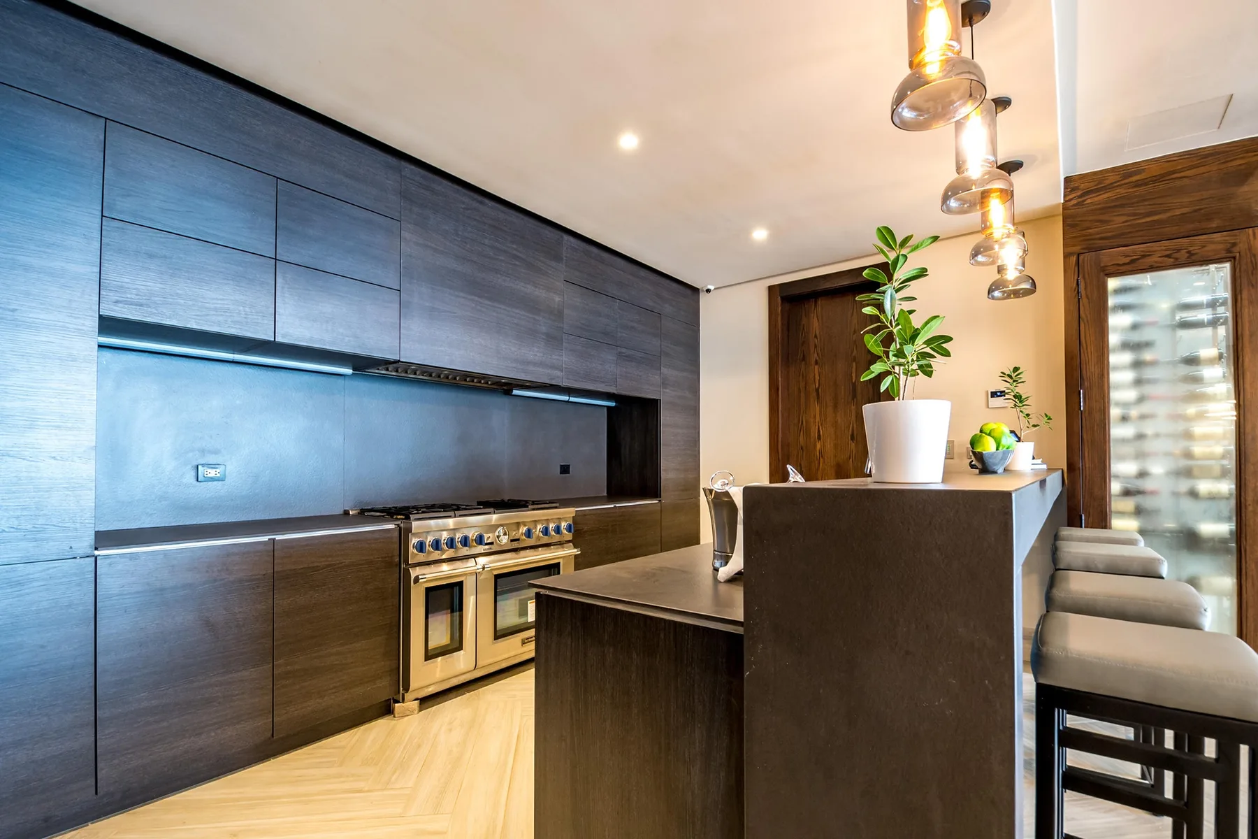 A modern kitchen with dark cabinetry, a central island, and bar seating.