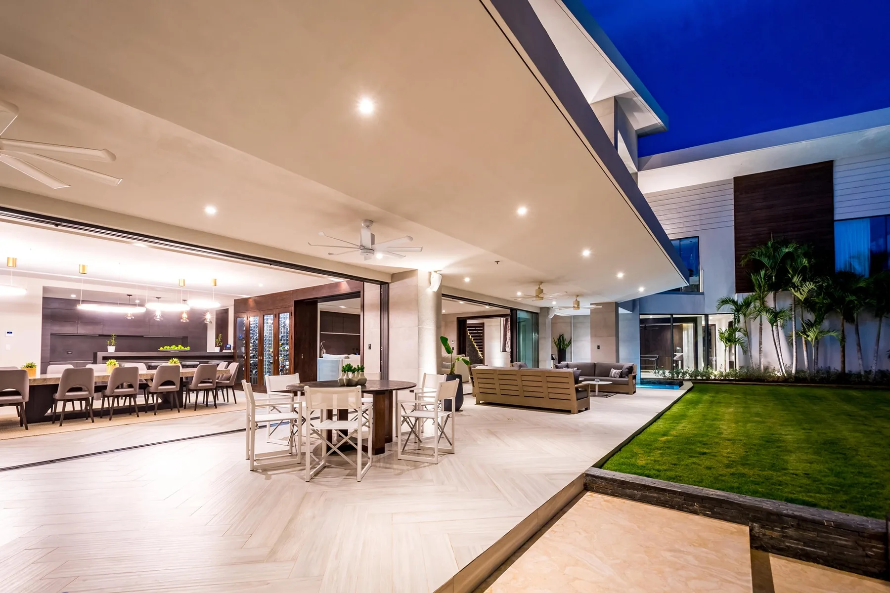An open-plan living and dining area opens onto a lawn.