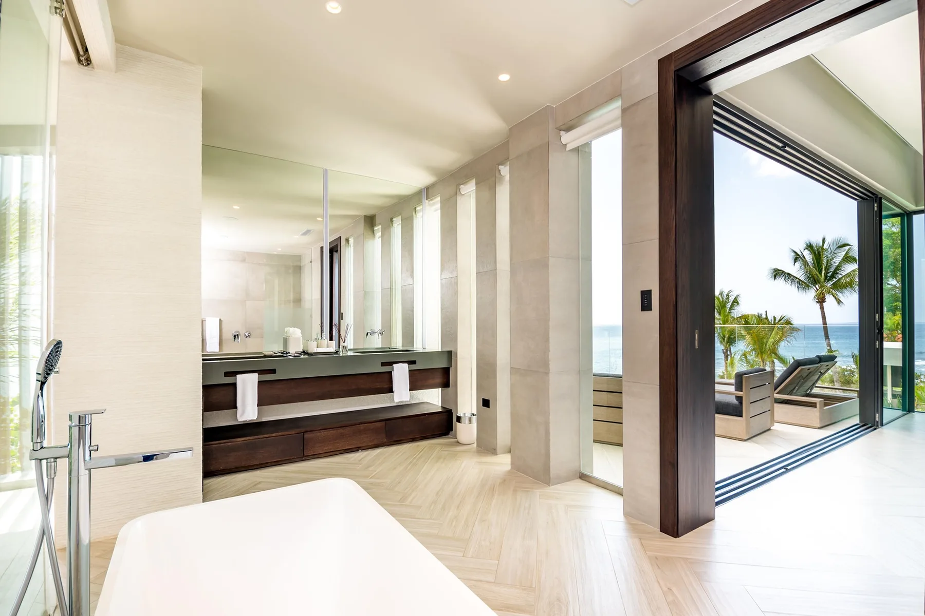 A spacious bathroom with a double vanity and an open view toward a terrace.