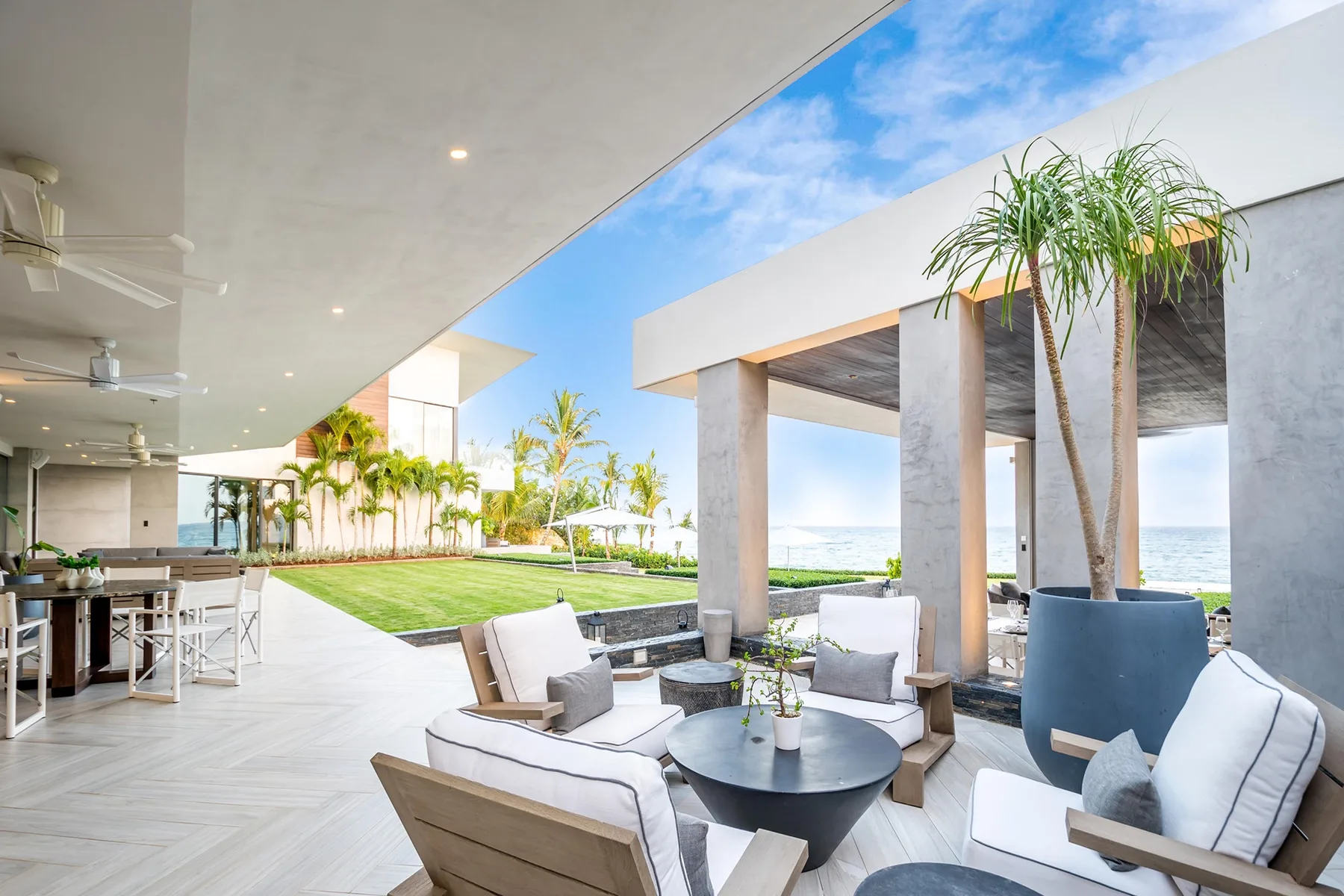 An open-air lounge beside a landscaped lawn, with seating overlooking the ocean.