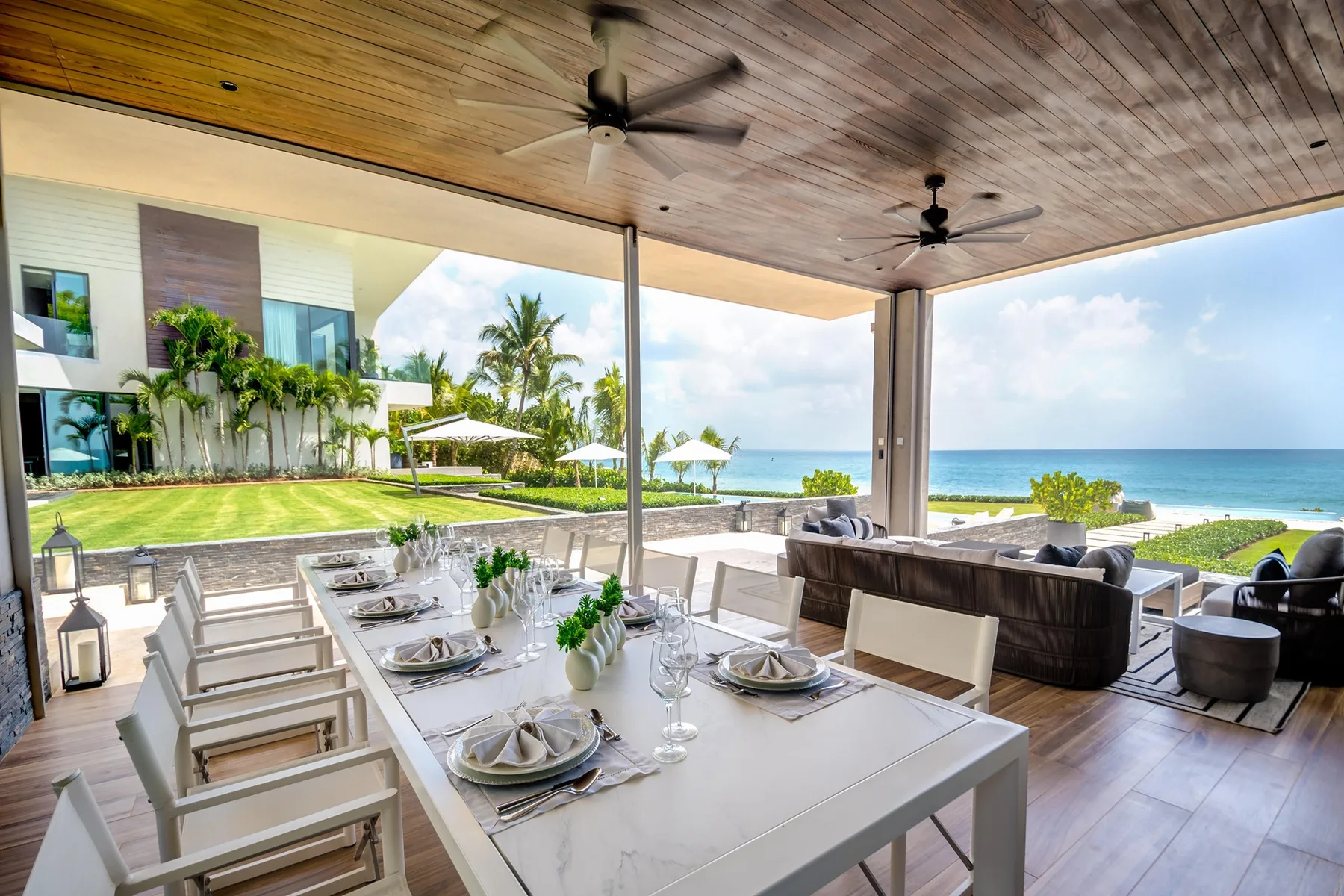 A covered outdoor dining area opens onto a lawn and ocean view.