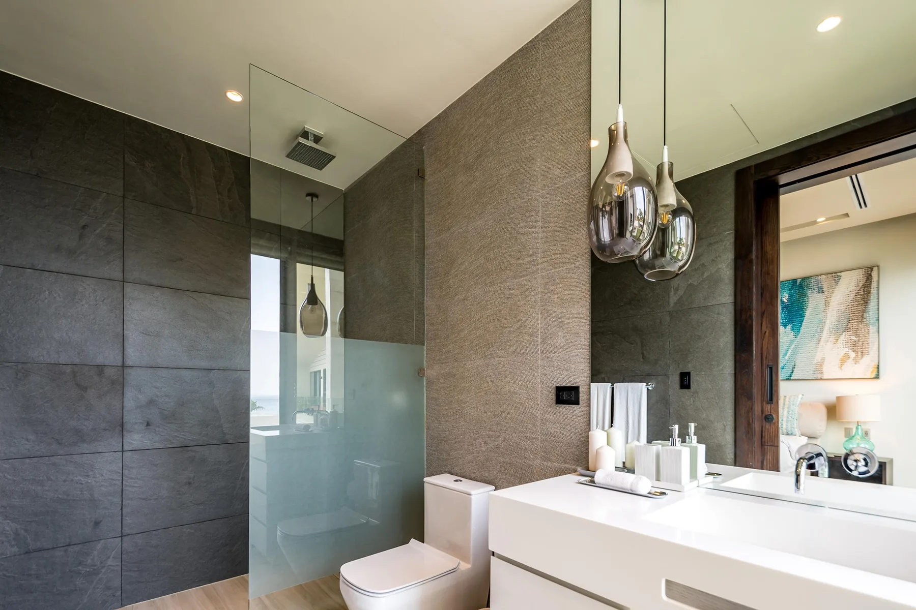 A modern bathroom with a glass shower, toilet, and wide sink vanity.