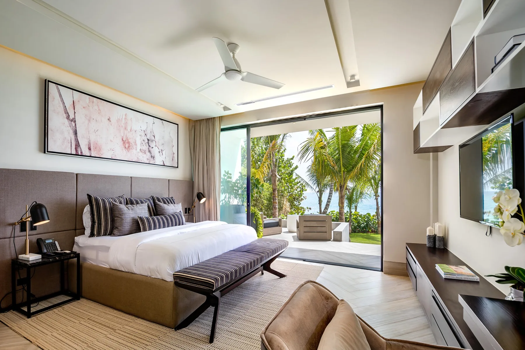 A bedroom with a large bed facing glass doors and a tropical garden.