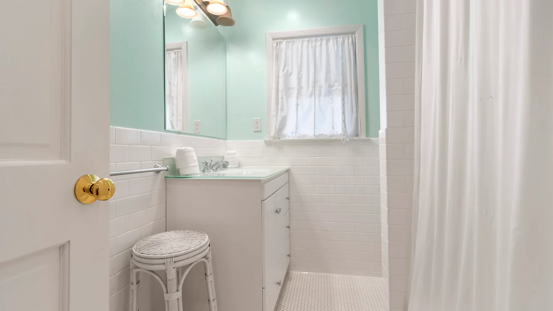 Un baño luminoso con lavabo, espejo y cortina de ducha.