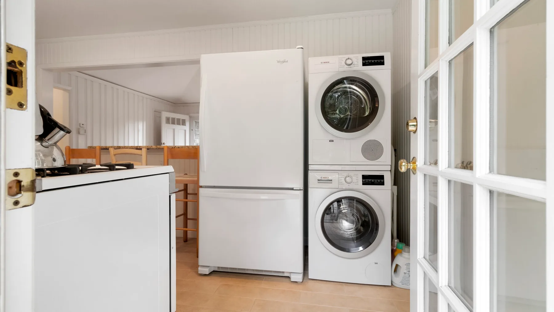 Zona de lavandería con lavadora y secadora apiladas junto a un refrigerador.