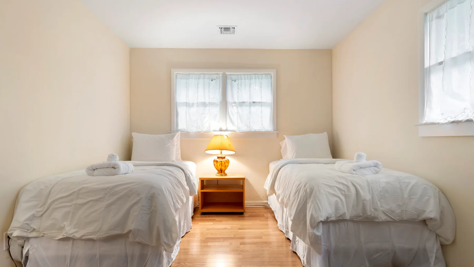 Un dormitorio luminoso con dos camas y una mesa pequeña entre ellas.