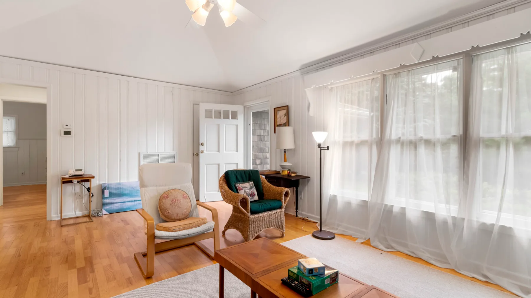Una sala luminosa con asientos, una mesa de centro de madera y cortinas translúcidas.
