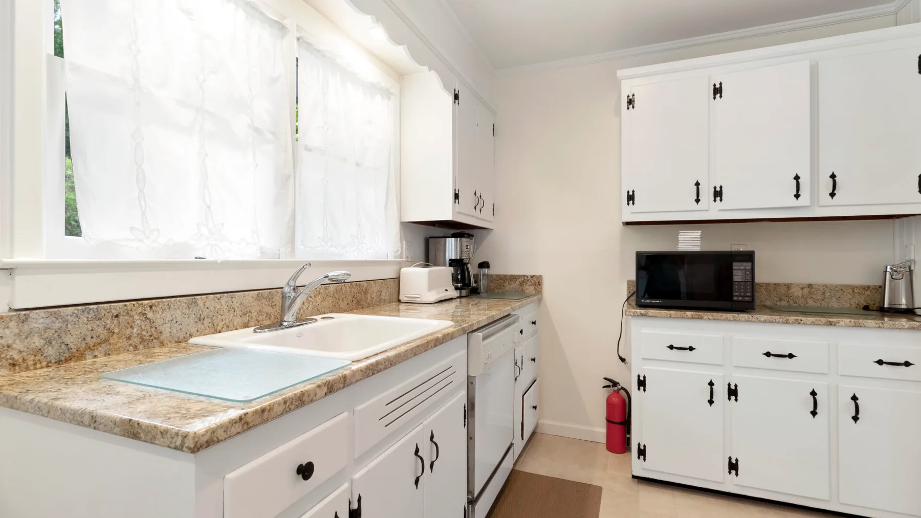 Una cocina luminosa con gabinetes blancos, una encimera y un fregadero.