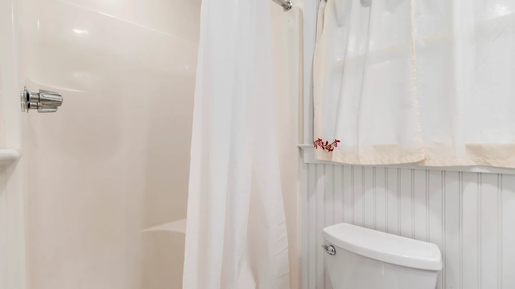 Un baño con una cortina de ducha y un inodoro.