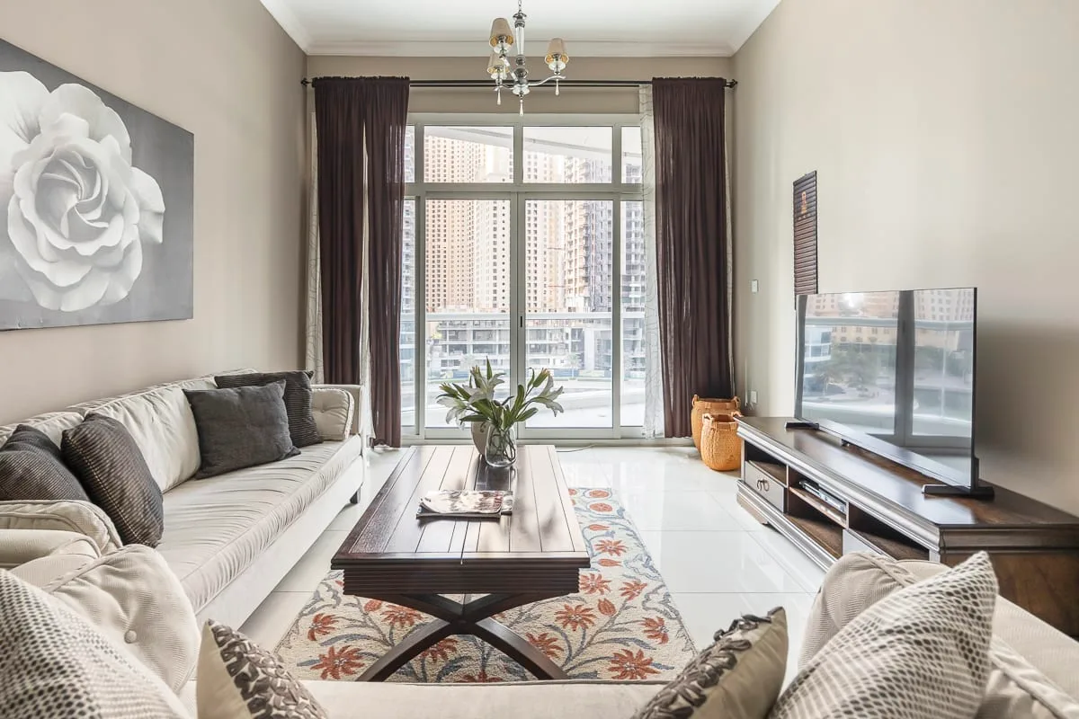 Una luminosa sala de estar con asientos alrededor de una mesa de centro junto a grandes ventanas.