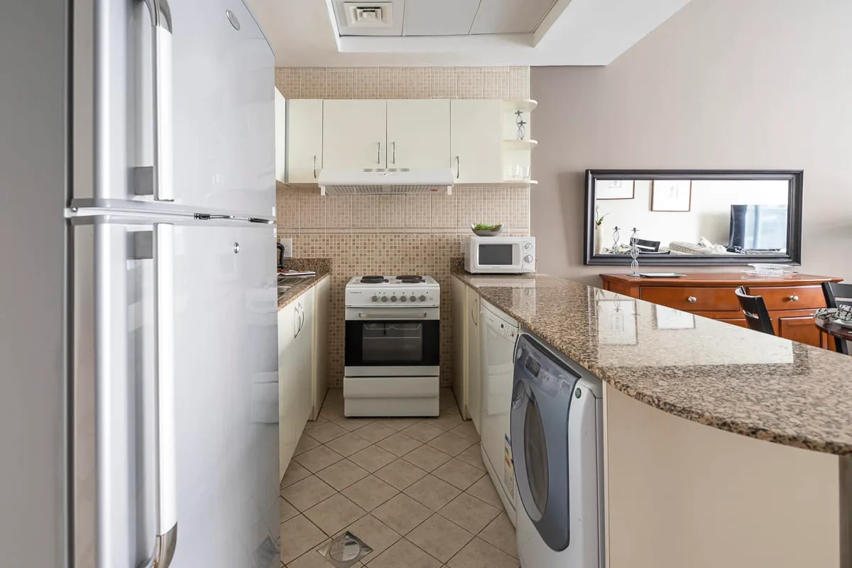 Una cocina compacta con refrigerador, estufa y una encimera junto a un comedor.