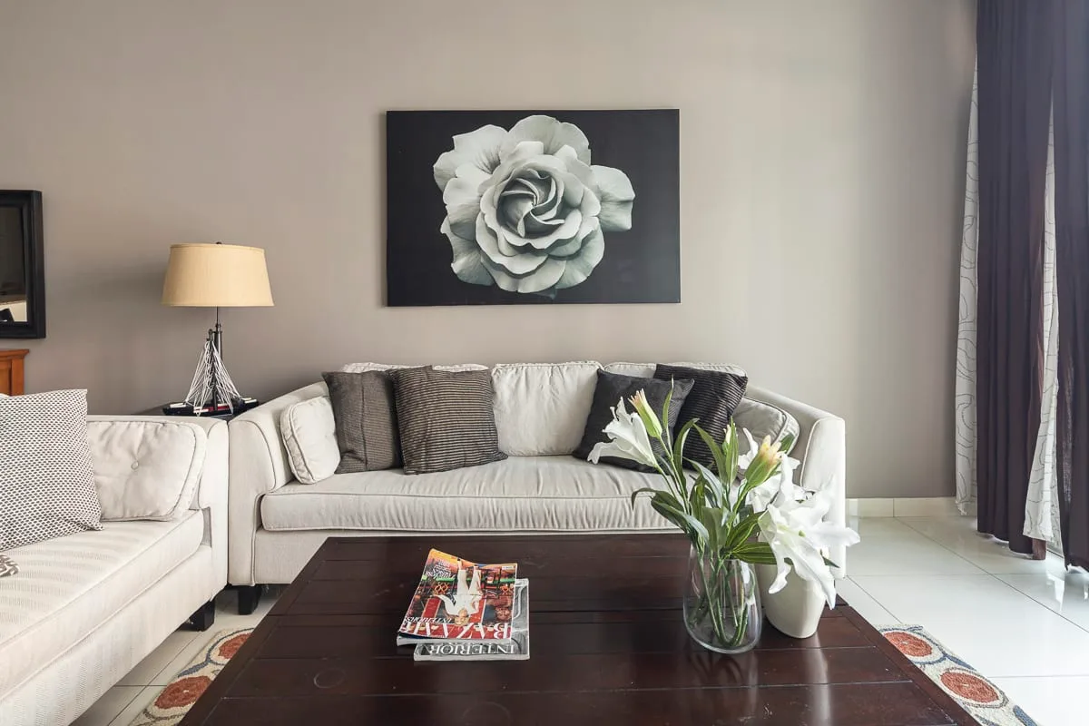 A living room with light seating, a dark coffee table, and a flower arrangement.