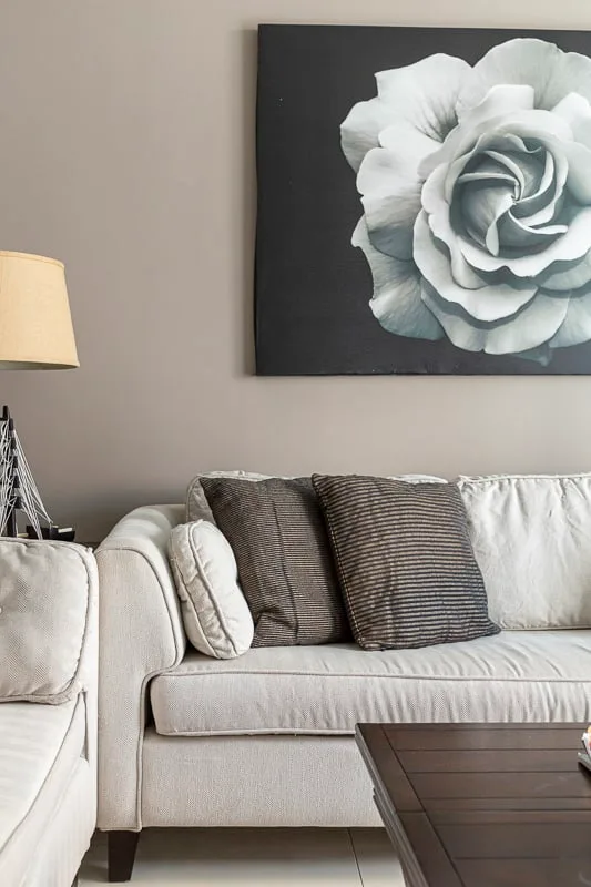 Una sala de estar con asientos claros y una gran obra floral en la pared.