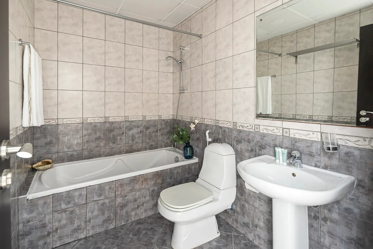Un baño alicatado con bañera, inodoro y lavabo con pedestal.