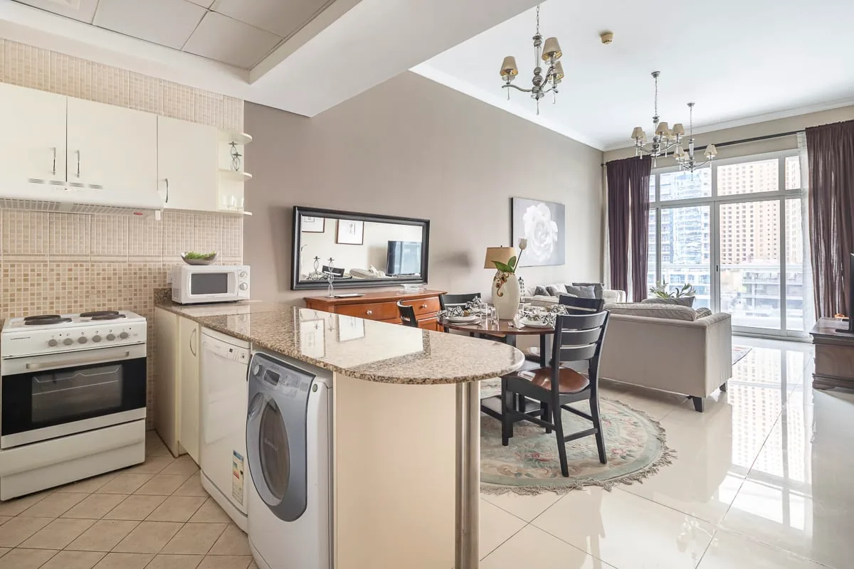 Una cocina abierta al salón, con una mesa de comedor junto a grandes ventanas.