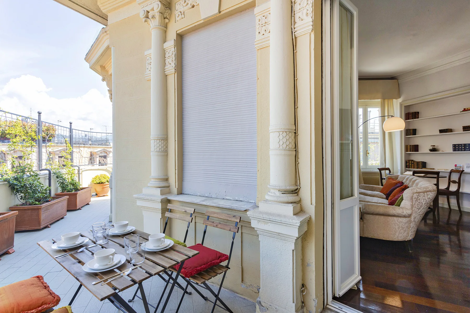 A furnished balcony with a small dining table beside an open doorway.