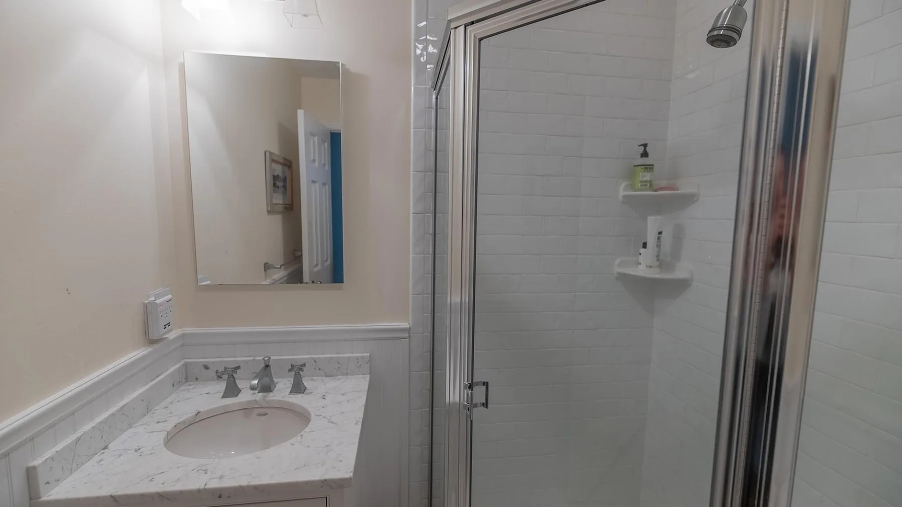 Un lavabo de baño está junto a una ducha con azulejos.