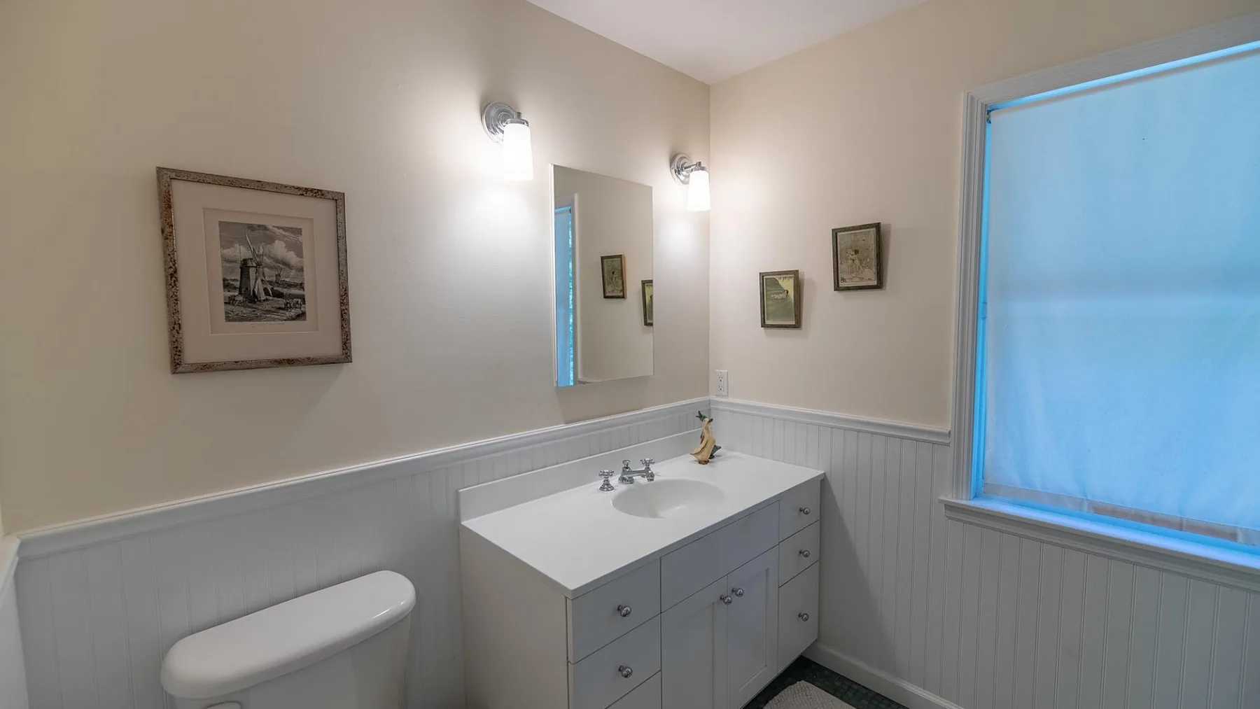 Un baño con lavabo, espejo, inodoro y una ventana con cortina azul.
