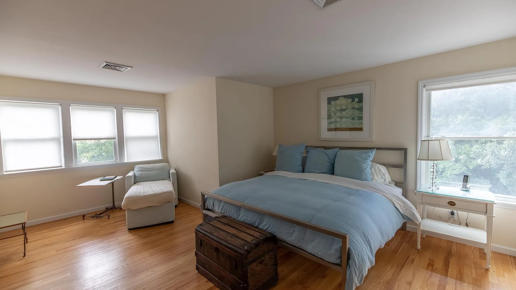 Un dormitorio con una cama, una pequeña zona de descanso y varias ventanas.
