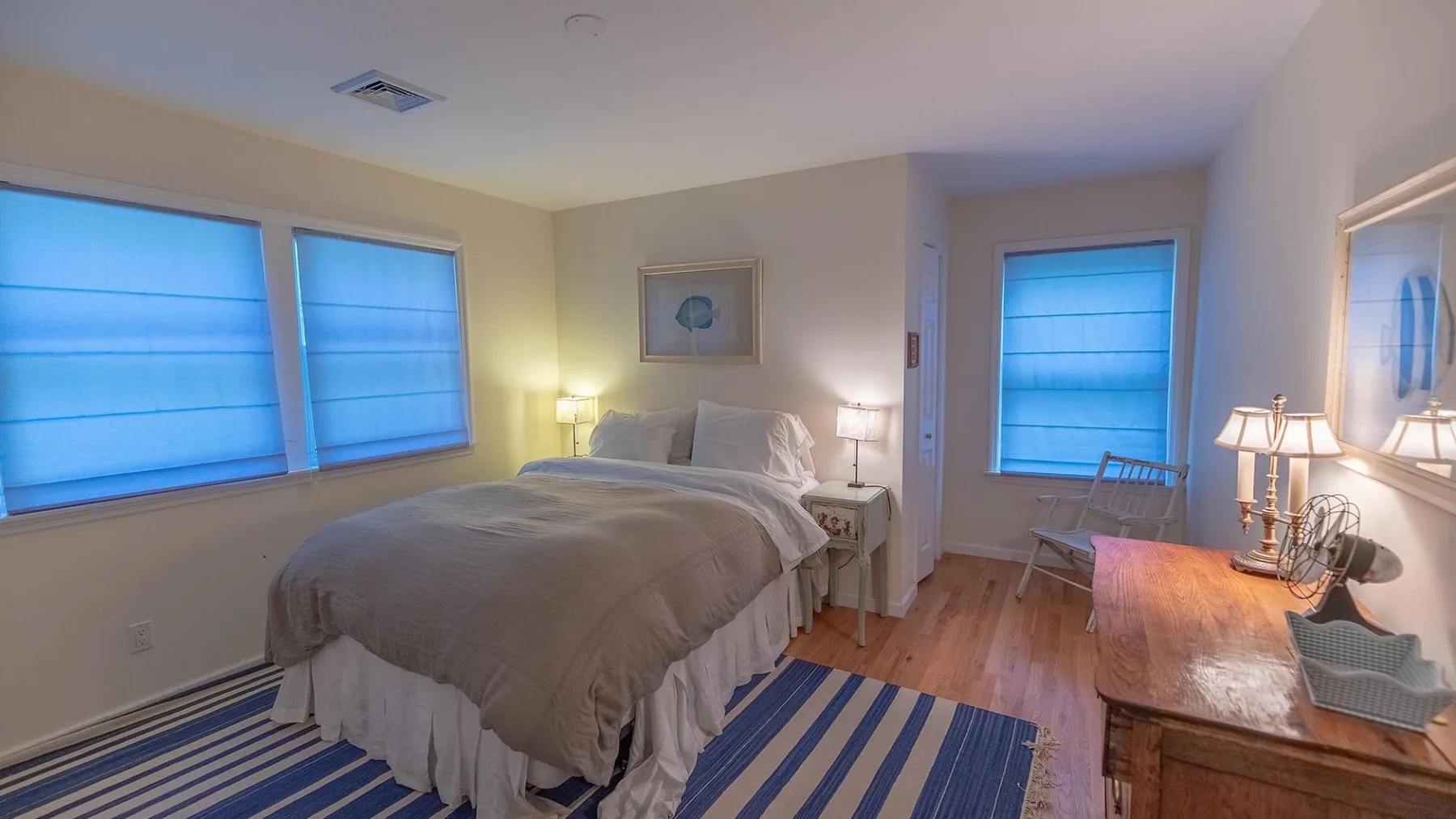 Un dormitorio con una cama, persianas azules y un escritorio de madera.