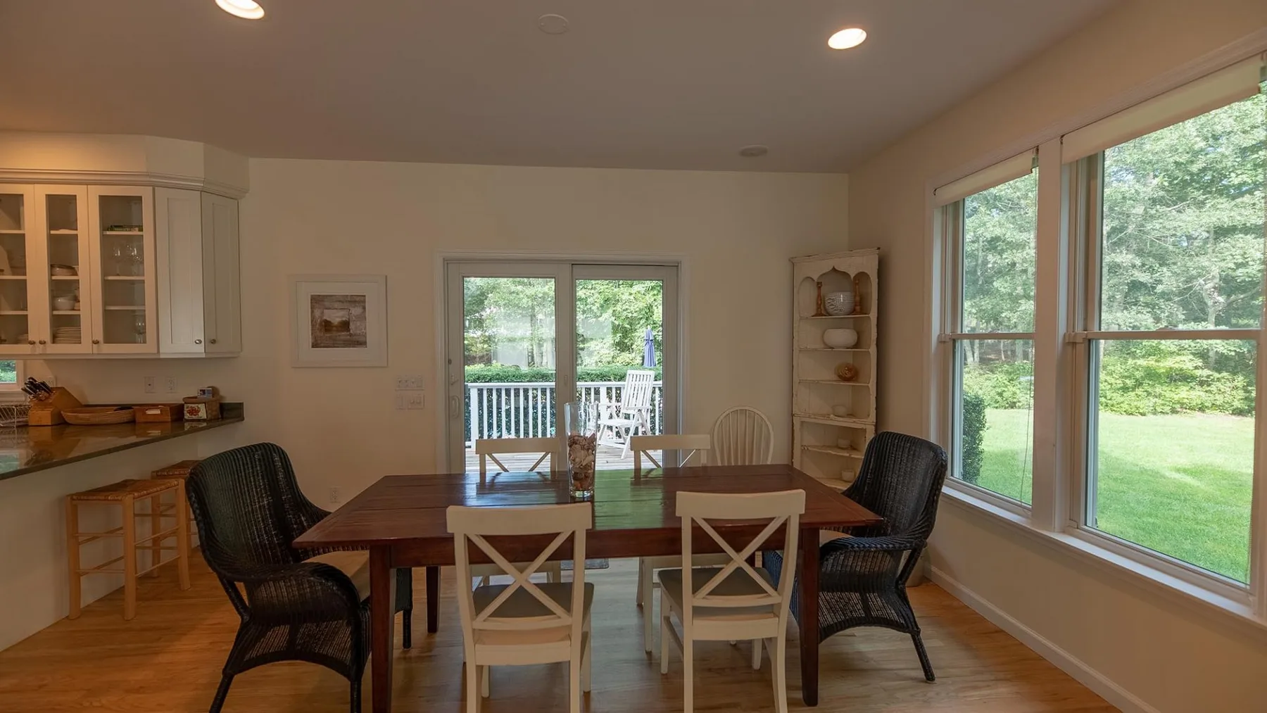 Un comedor con una mesa de madera y grandes ventanas con vista al jardín.