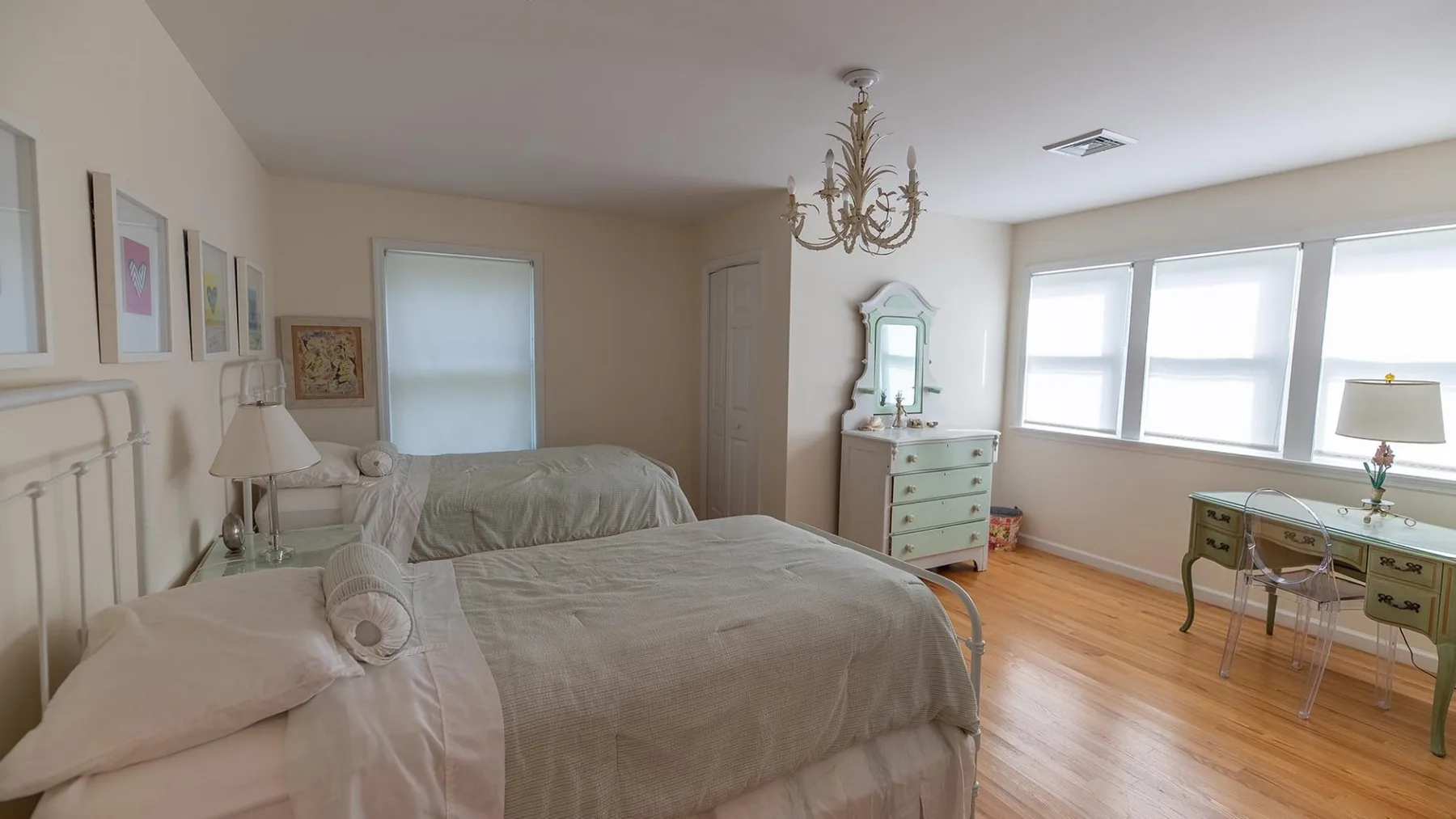Un dormitorio con una cama grande, una cómoda y un escritorio junto a las ventanas.