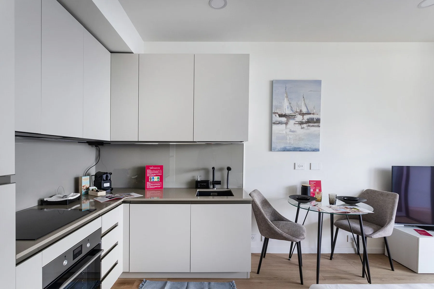 A modern kitchen and dining area with white cabinetry and a small table.