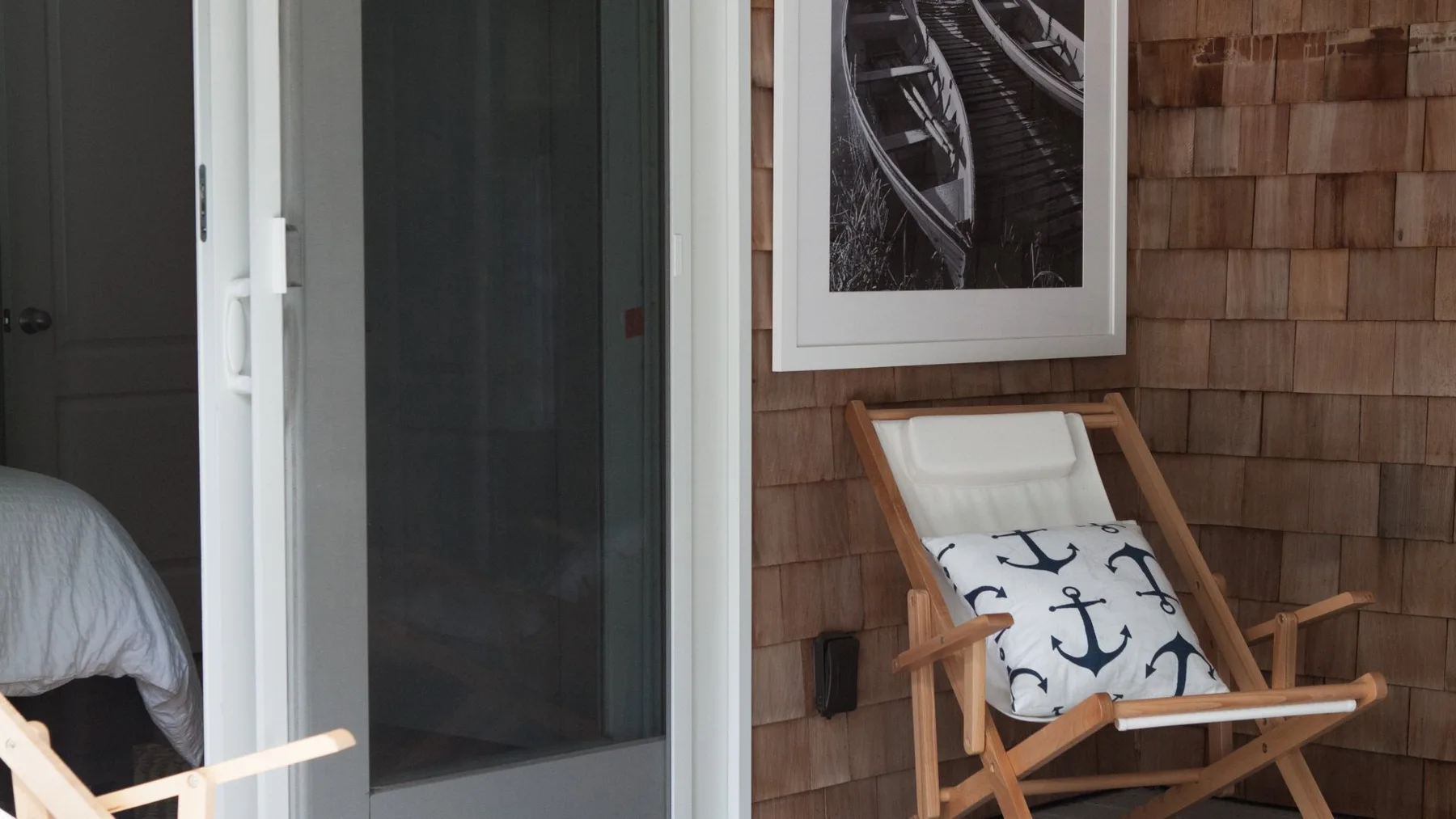Un dormitorio con una cama junto a una silla de madera y un cuadro enmarcado.