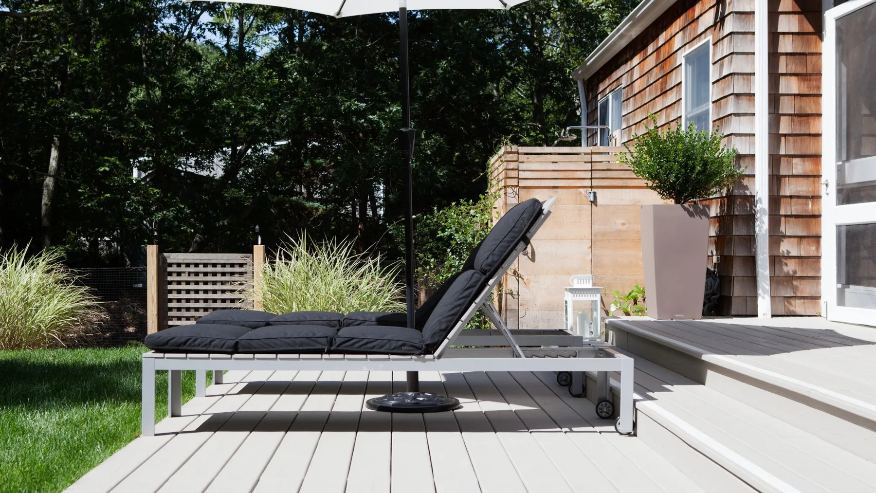 Una terraza exterior con una tumbona reclinable junto a un edificio revestido de madera.