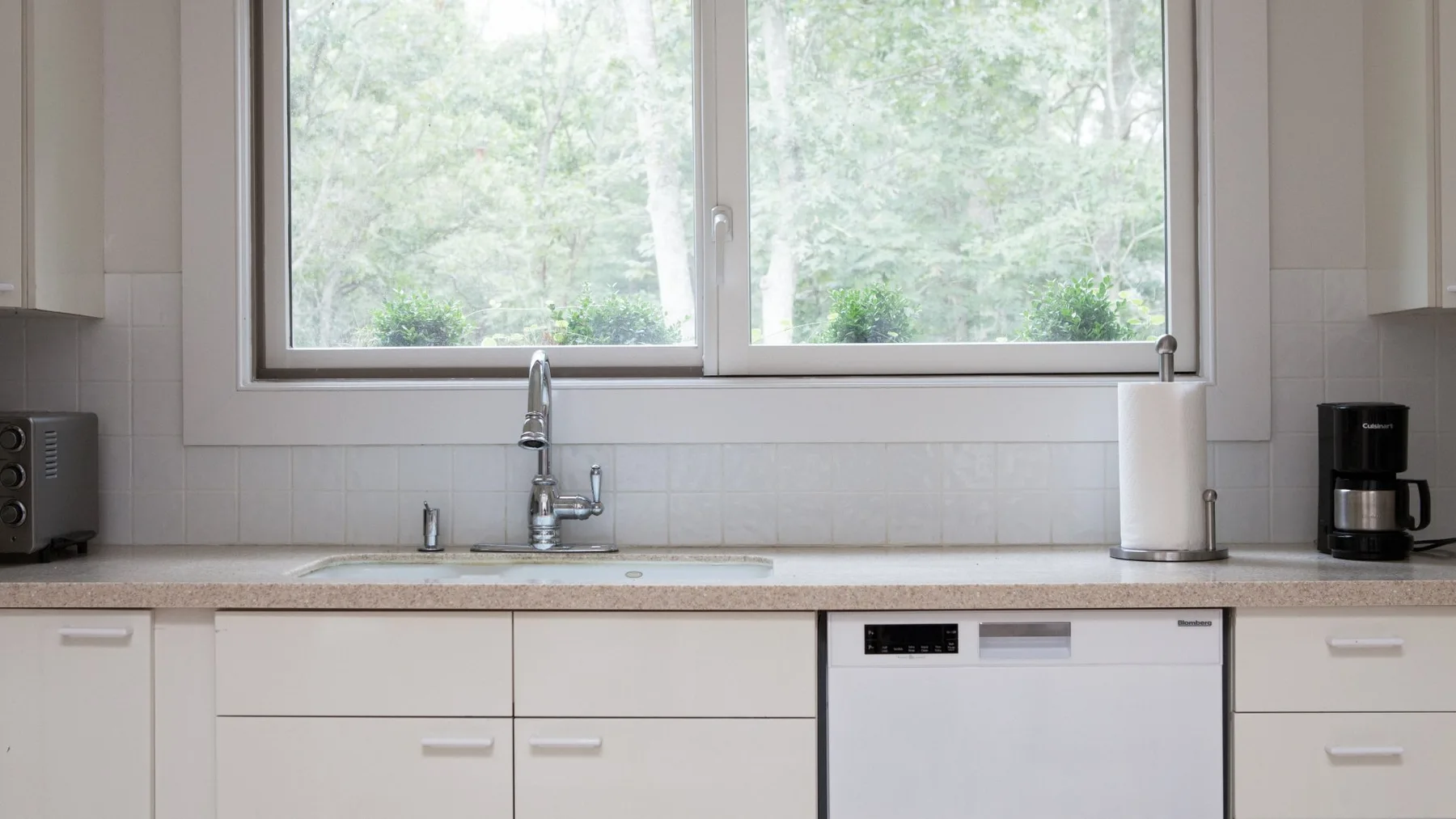 Una cocina luminosa con una ventana amplia sobre el fregadero y la encimera.
