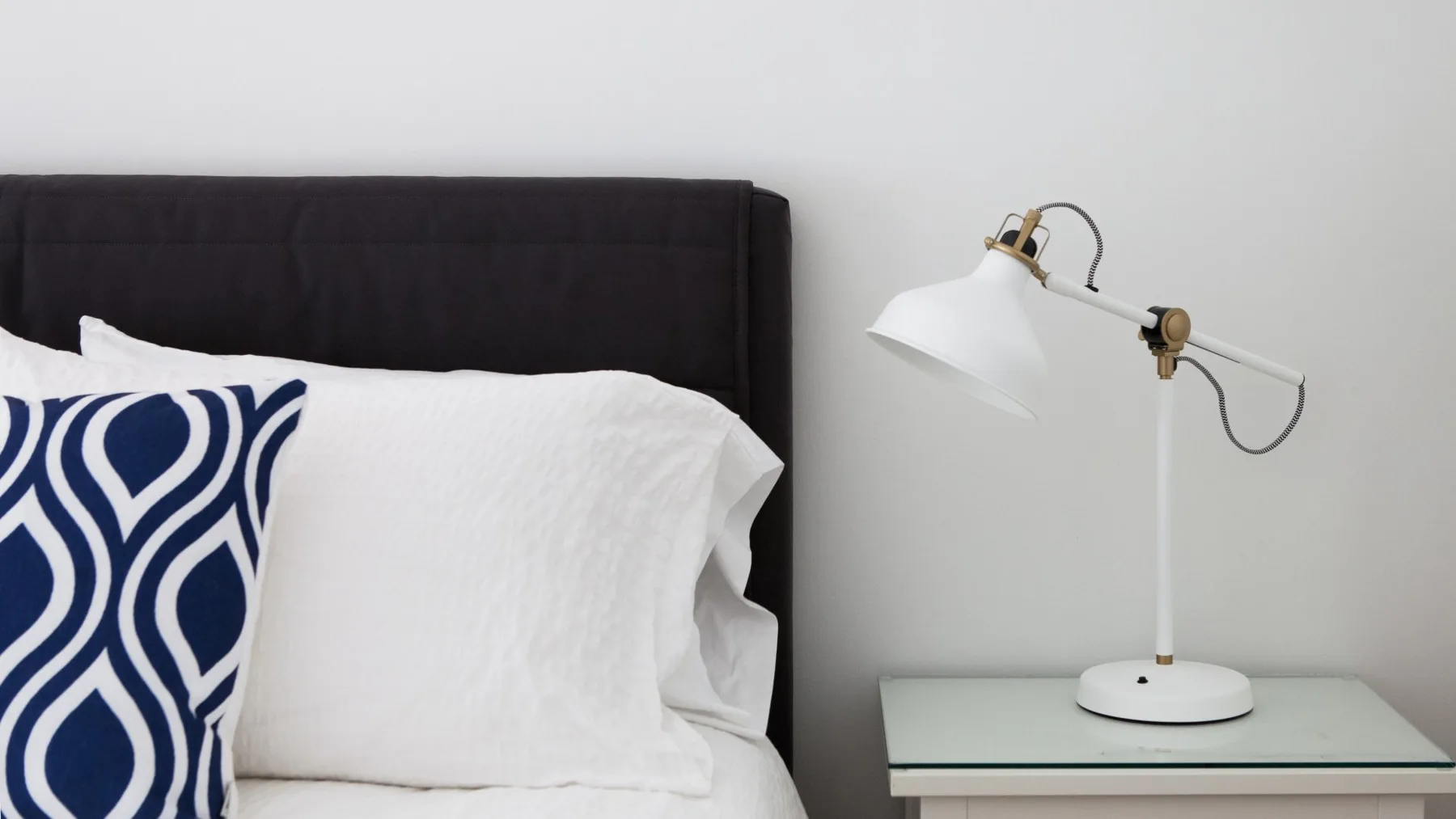 Una cama con ropa de cama blanca y una lámpara de mesita.