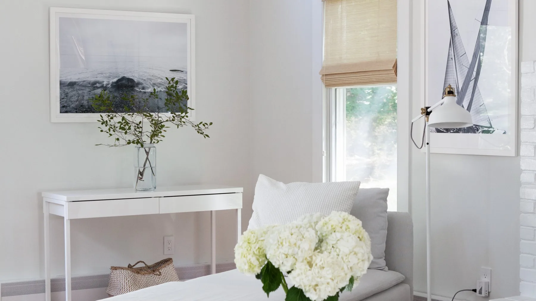 Una sala luminosa cuenta con una zona de asientos gris y una consola blanca.