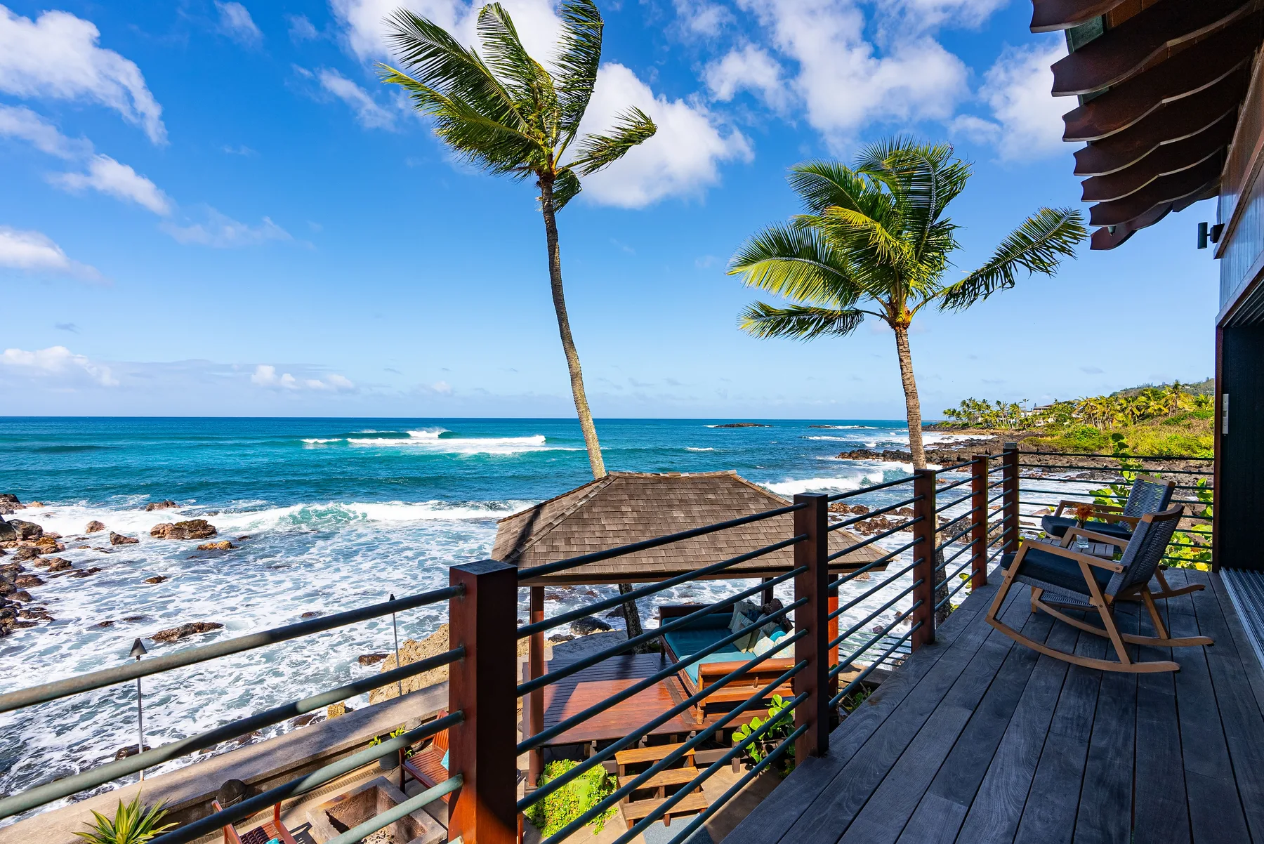 Una terraza frente al mar da a la costa rocosa y al agua azul.