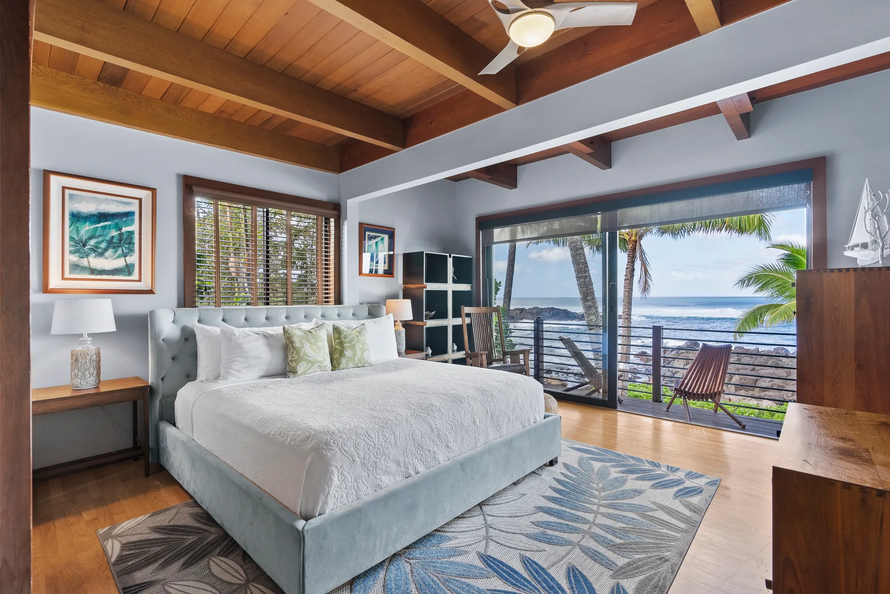 Un dormitorio con una cama grande y puertas corredizas de vidrio con vista al mar.