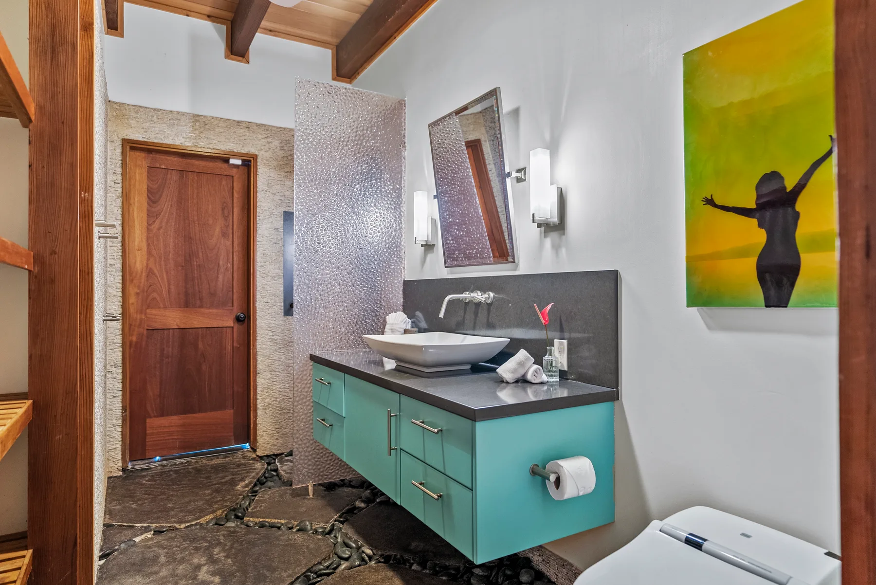 Un lavabo de baño con espejo está junto a una puerta de madera.