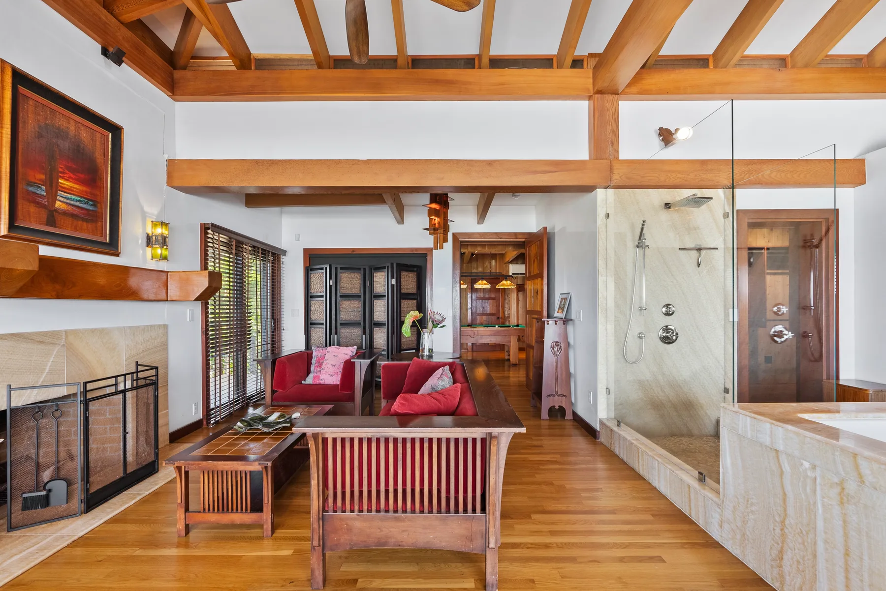 Una sala luminosa con vigas de madera expuestas, asientos y una zona de ducha acristalada.