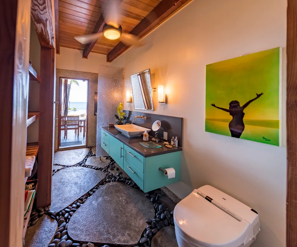 Un baño cuenta con un tocador turquesa, un lavabo y un inodoro.
