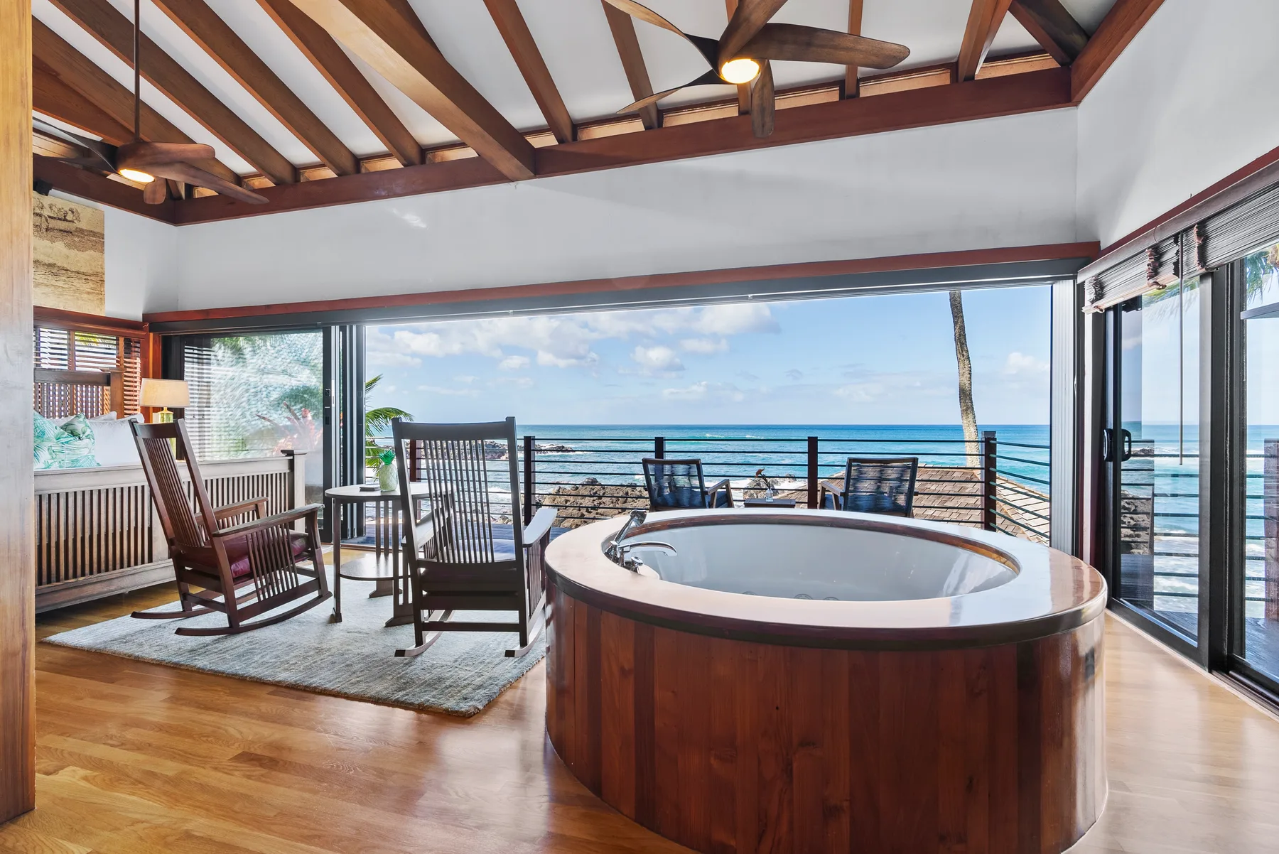 Una sala amplia cuenta con una bañera redonda, asientos y vistas al mar.