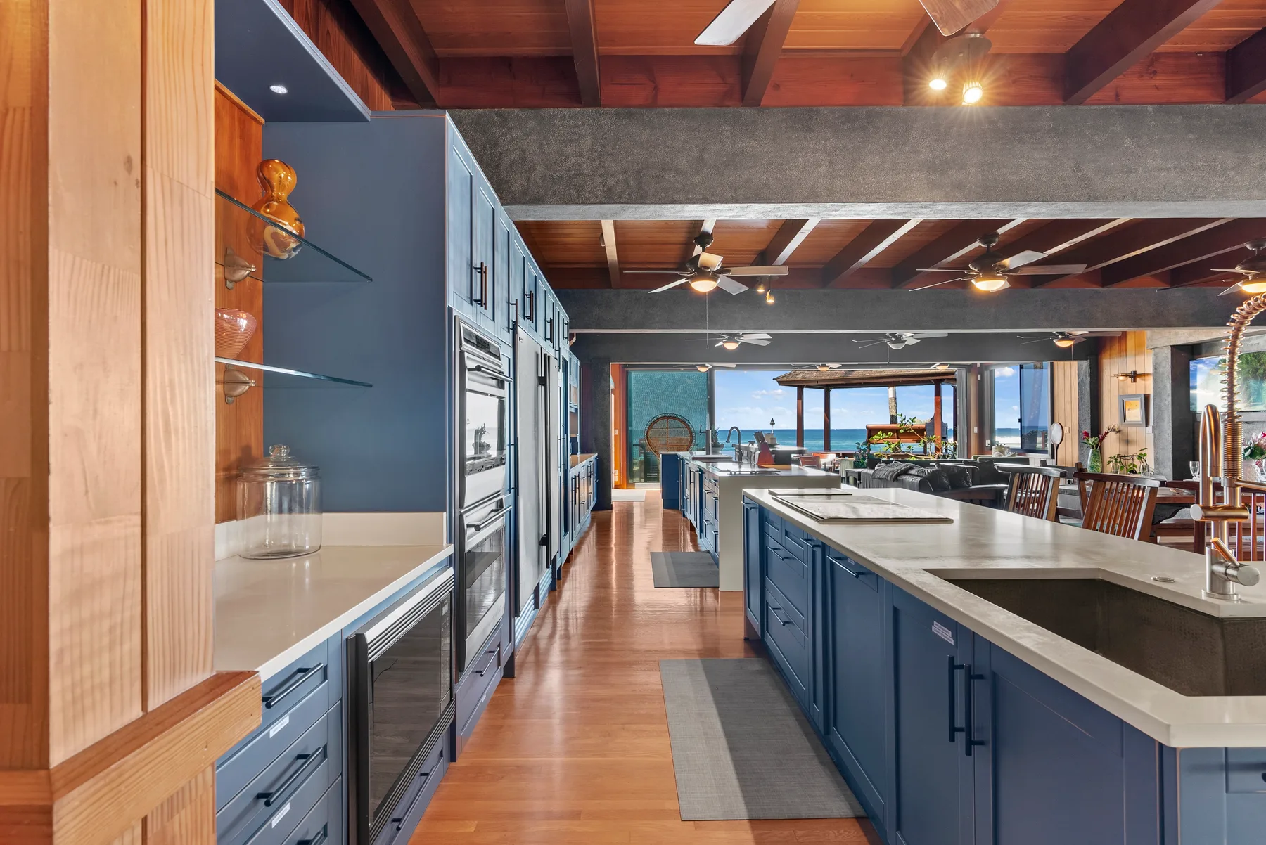 Una cocina amplia con una isla larga y un comedor al fondo.
