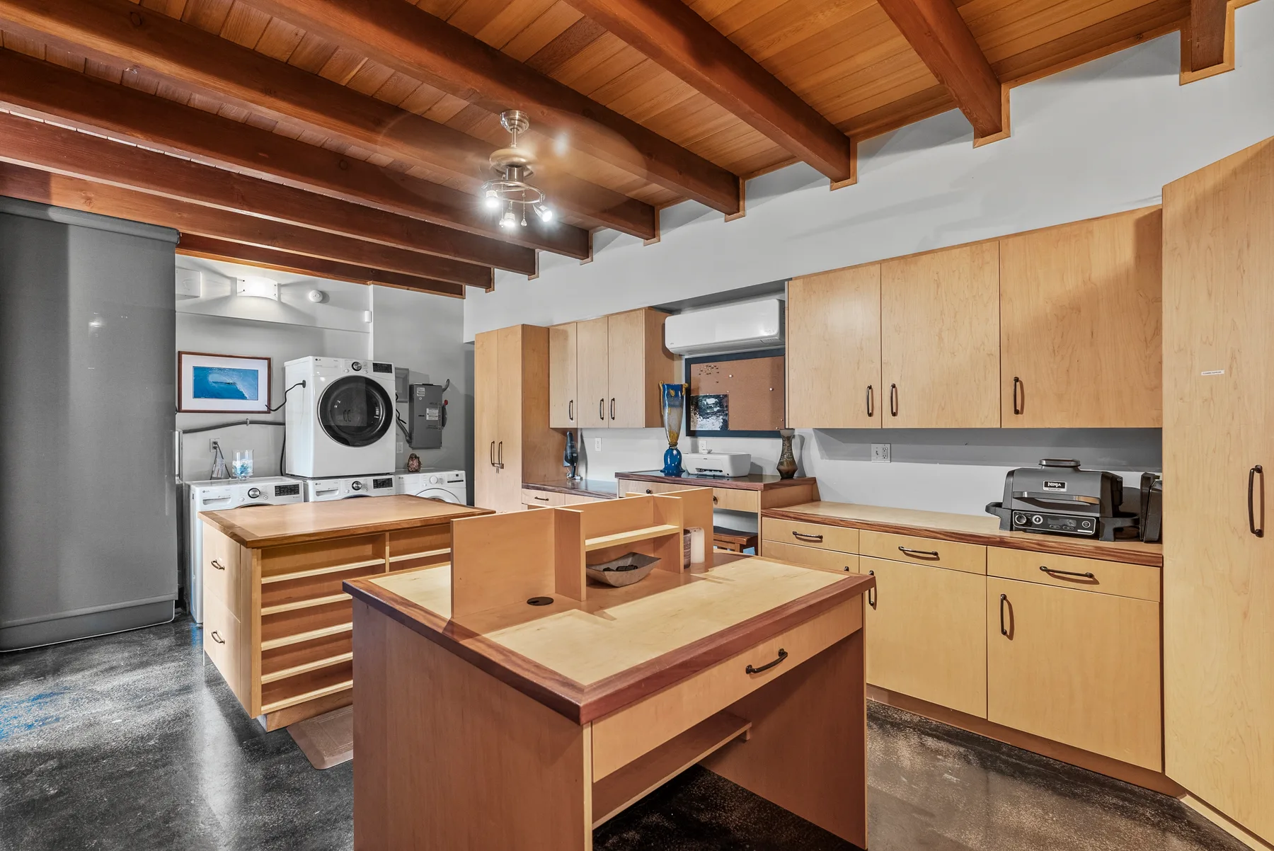 Una cocina amplia con gabinetes de madera, mostradores centrales y vigas expuestas en el techo.