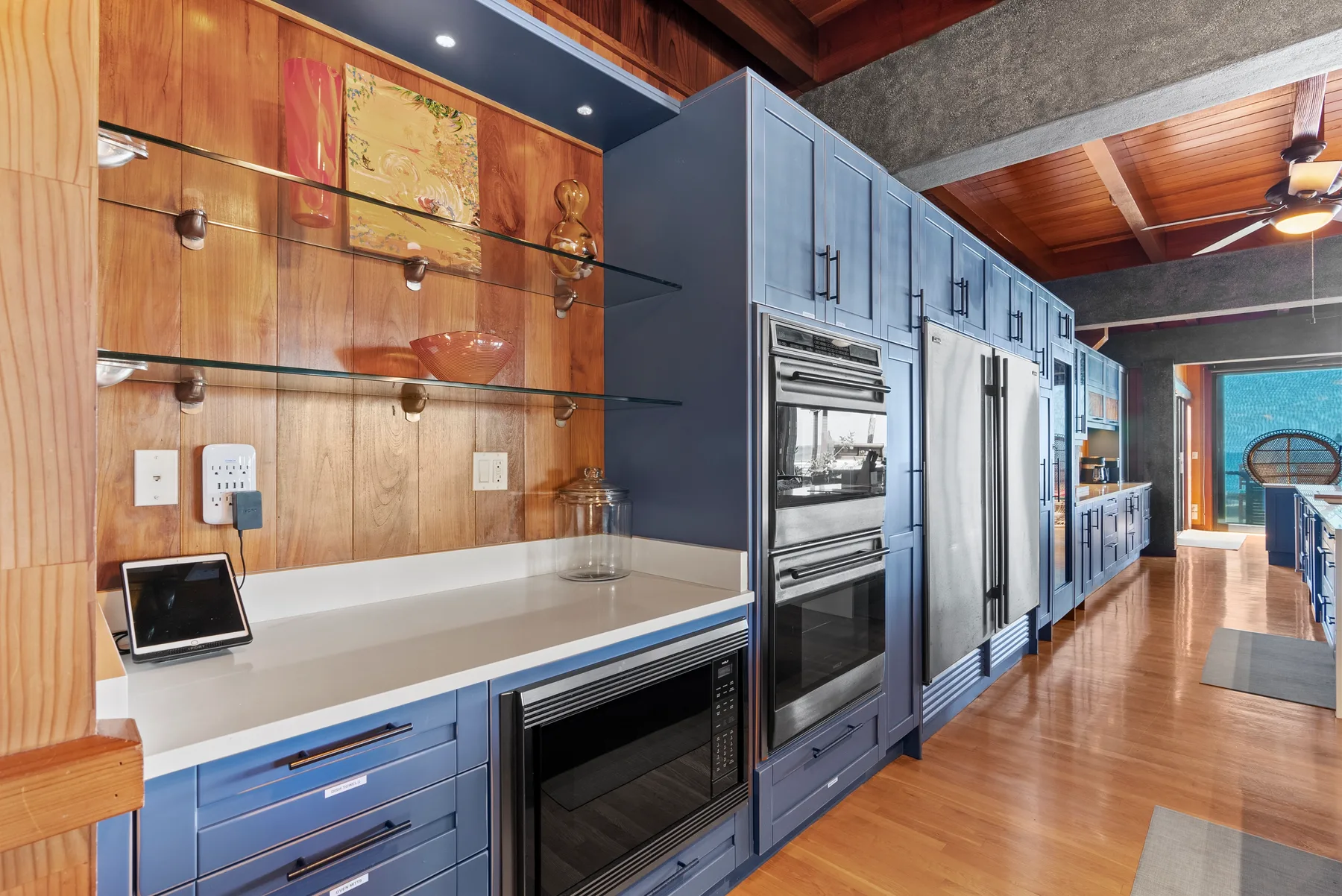 Una cocina con gabinetes azules, electrodomésticos de acero inoxidable y una encimera larga.